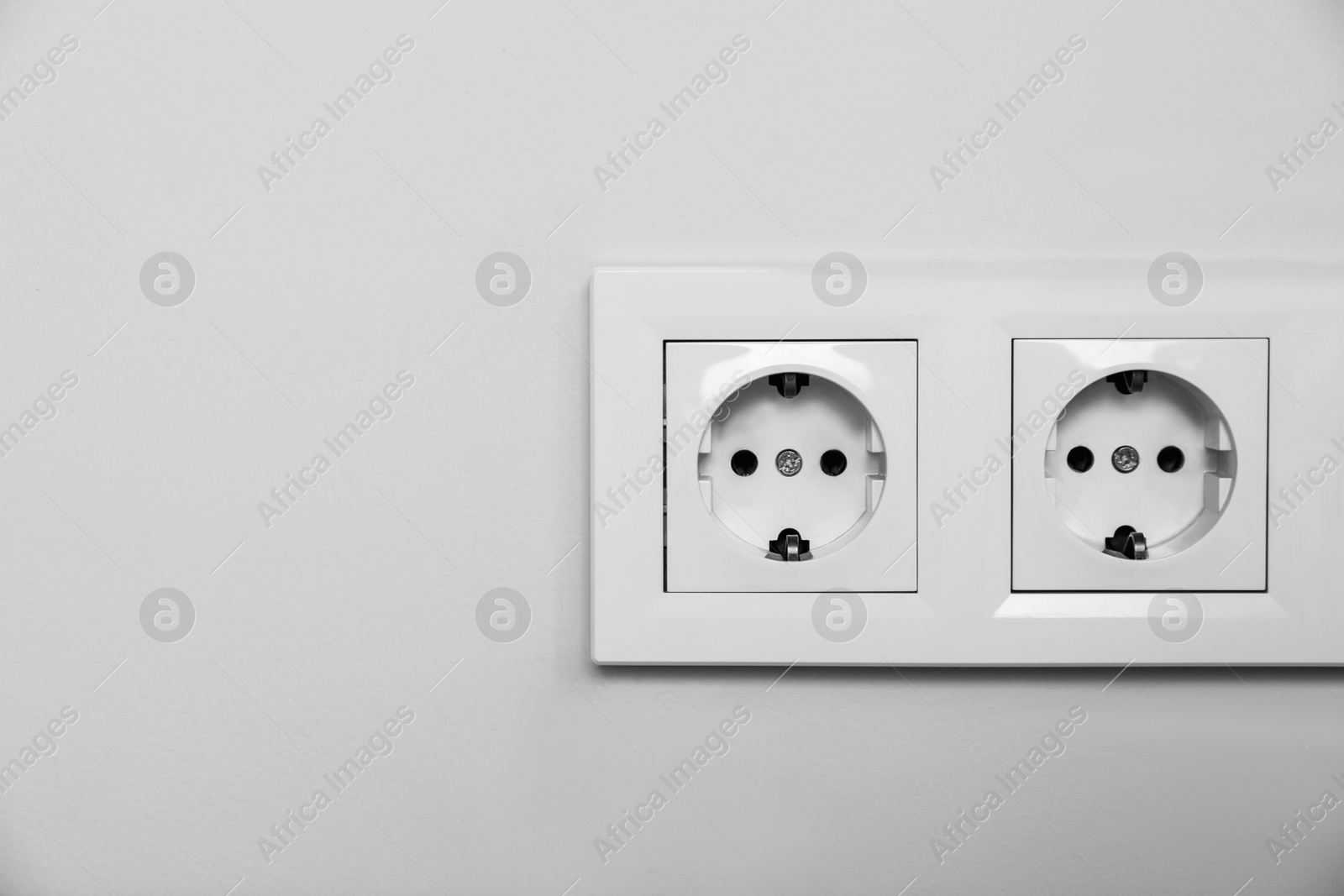 Photo of Power sockets on white wall, space for text. Electrical supply