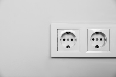 Photo of Power sockets on white wall, space for text. Electrical supply