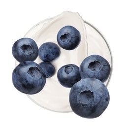 Image of Delicious ripe blueberries falling into bowl with yogurt on white background, top view