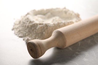 Photo of Rolling pin and flour on grey marble table, closeup