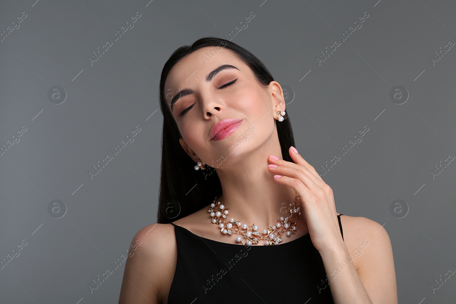 Photo of Beautiful young woman with elegant jewelry on dark grey background