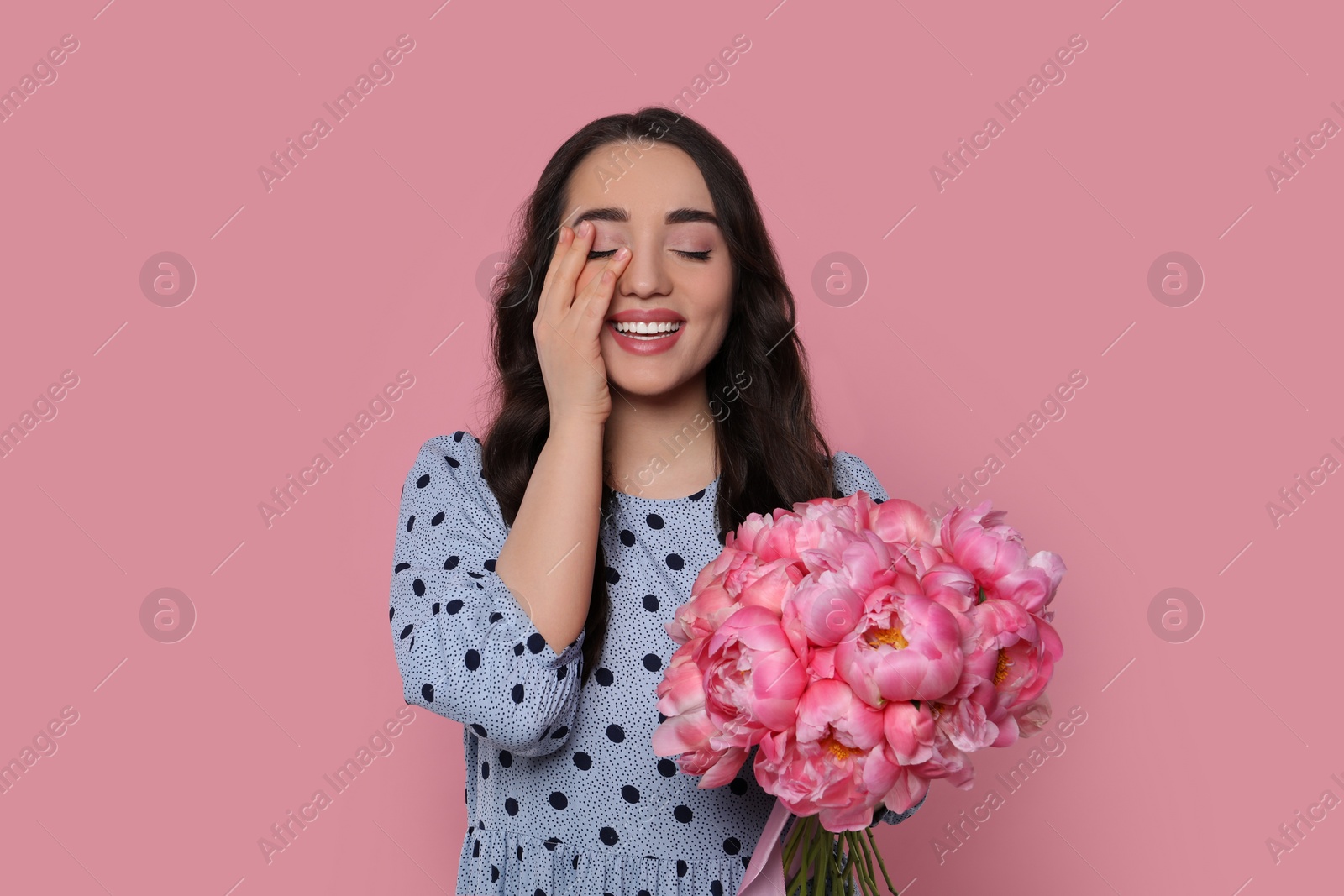 Photo of Beautiful young woman with bouquet of peonies on pink background