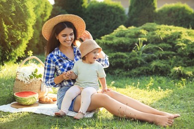 Mother with her baby daughter having picnic in garden on sunny day