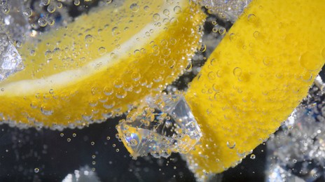 Image of Lemon slices in soda water against dark background, closeup. Banner design