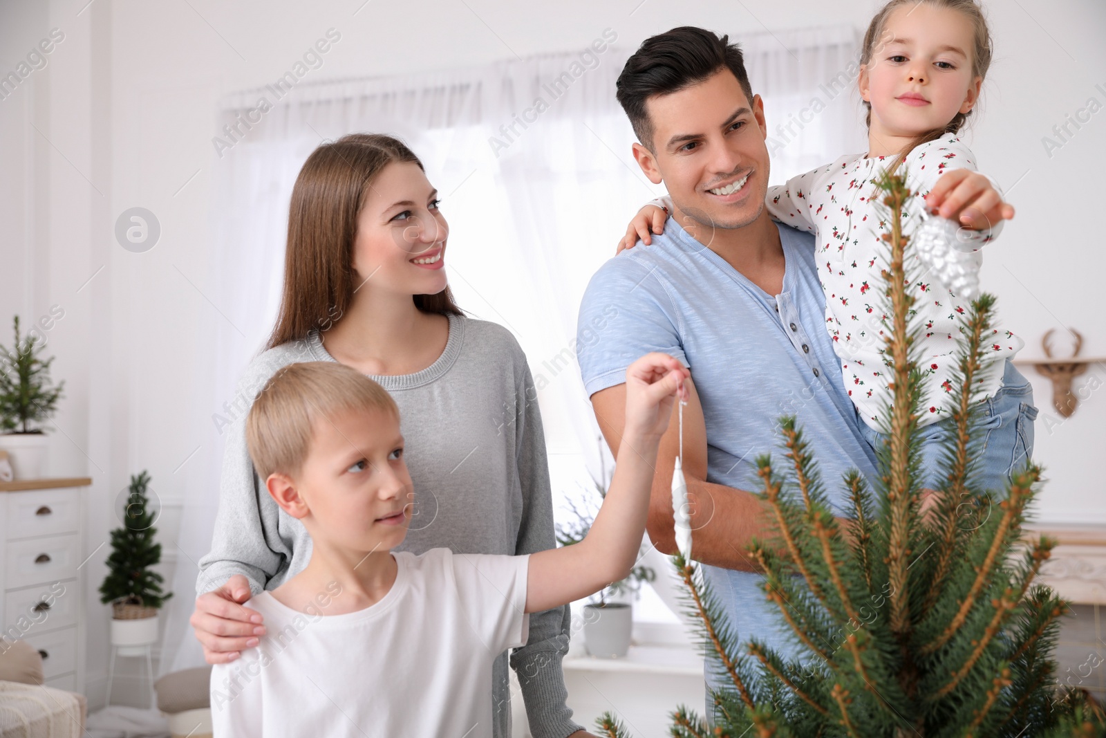 Photo of Happy family with cute children decorating Christmas tree together at home