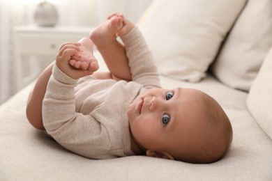 Photo of Adorable little baby lying on sofa at home