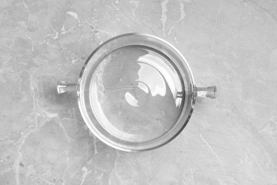 Glass pot with lid on light grey marble table, top view