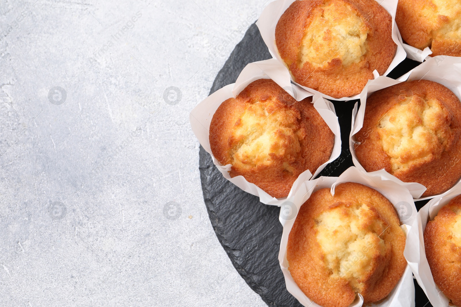 Photo of Delicious sweet muffins on light grey textured table, top view. Space for text