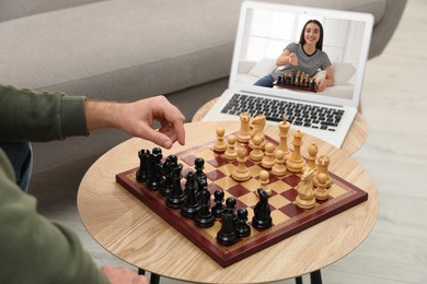 Image of Man playing chess with partner via online video chat in living room, closeup