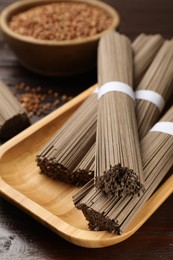 Photo of Uncooked buckwheat noodles (soba) and grains on wooden table, closeup