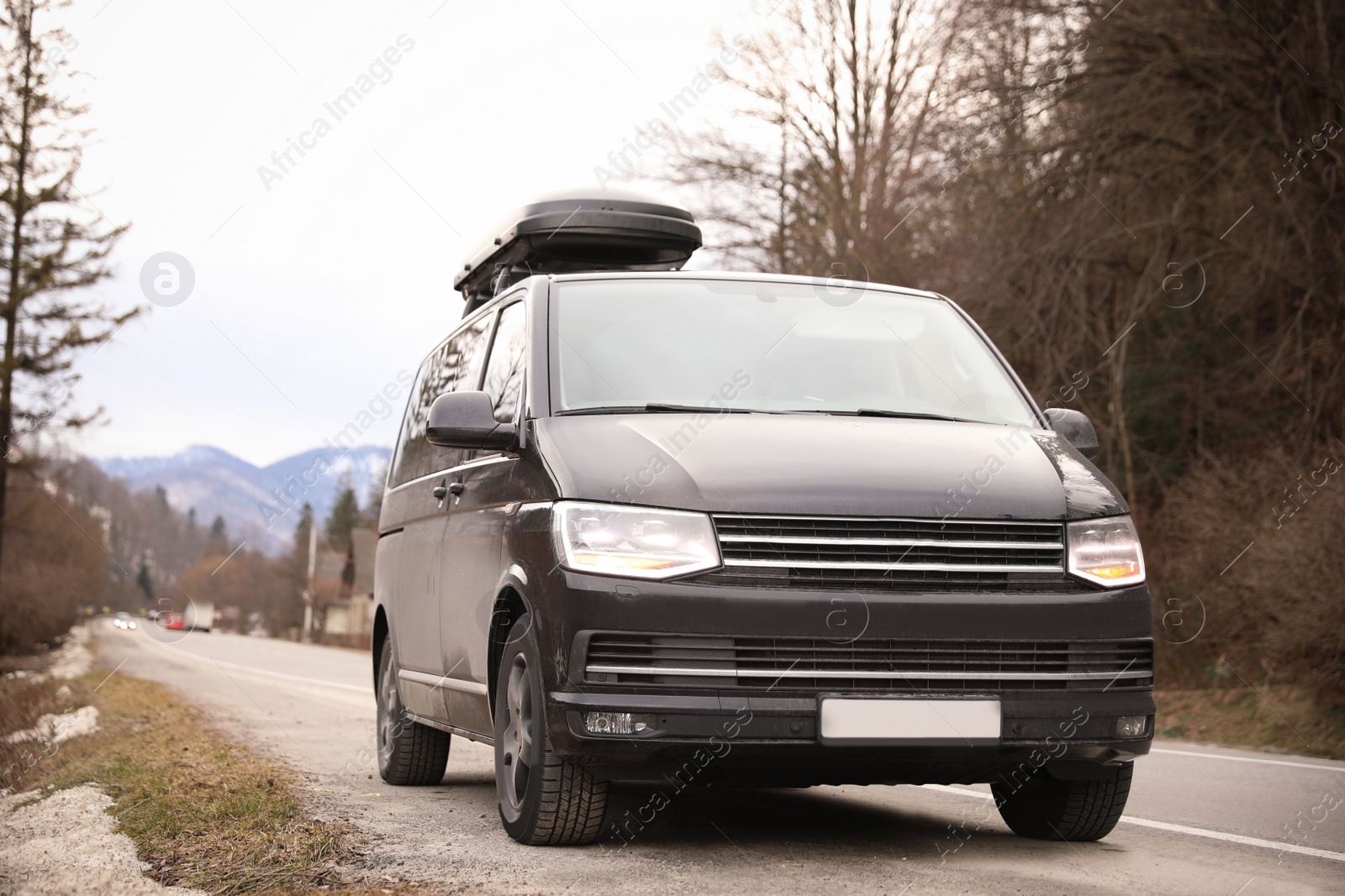 Photo of Black car with roof rack on road. Seasonal vacation