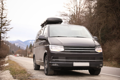 Black car with roof rack on road. Seasonal vacation