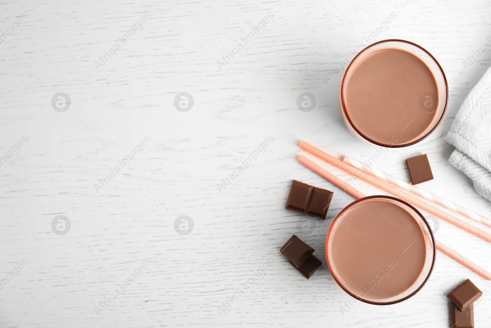 Photo of Flat lay composition with glasses of tasty chocolate milk and space for text on wooden background. Dairy drink