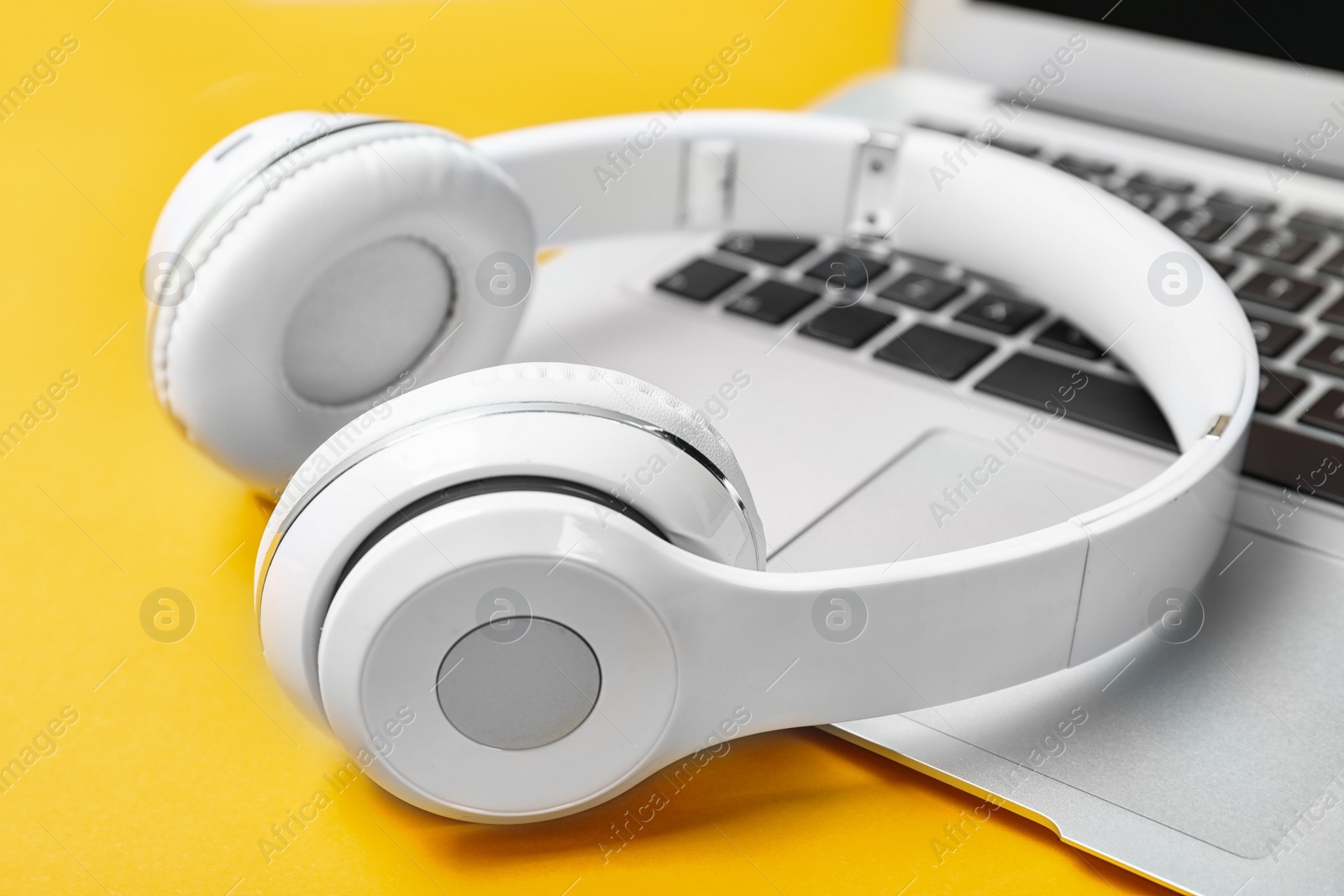 Photo of Modern headphones and laptop on color background, closeup