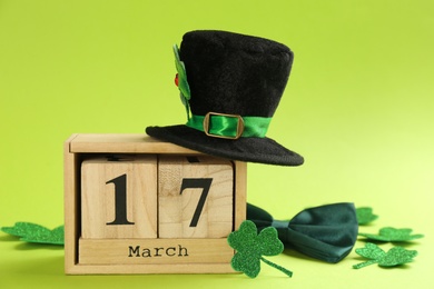 Photo of Leprechaun's hat, block calendar and St. Patrick's day decor on green background