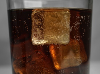 Photo of Glass of refreshing soda drink with ice cubes on grey background, closeup