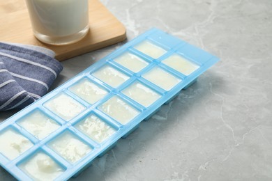 Ice cube tray with frozen milk on grey table