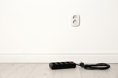 Extension cord near wall indoors, space for text. Electrician's professional equipment