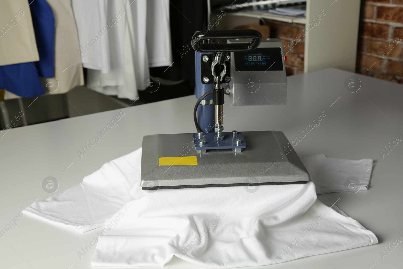 Photo of Printing logo. Heat press with t-shirt on white table