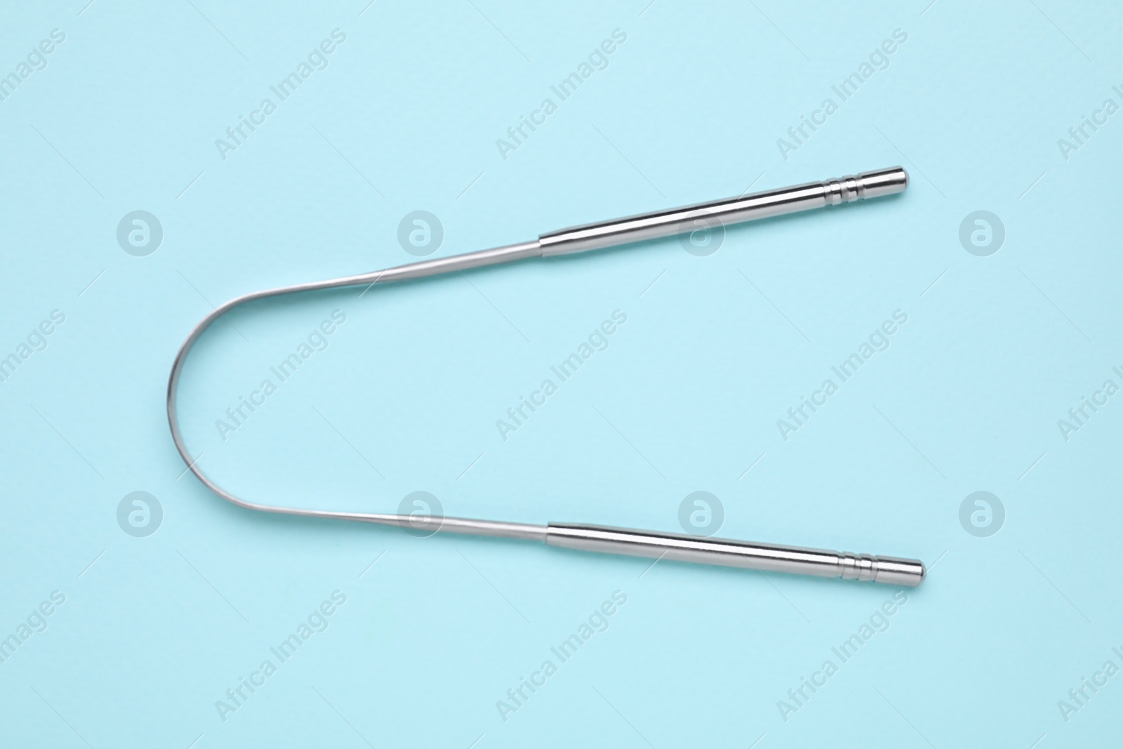 Photo of Metal tongue cleaner on light blue background, top view