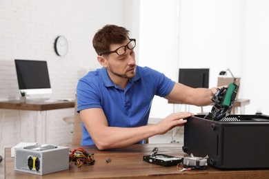 Male technician repairing computer at table indoors