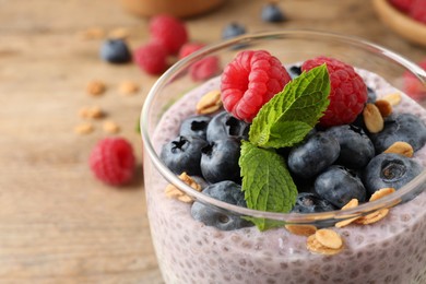 Photo of Delicious chia pudding with berries, granola in glass, closeup