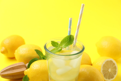 Photo of Natural freshly made lemonade on yellow background, closeup. Summer refreshing drink