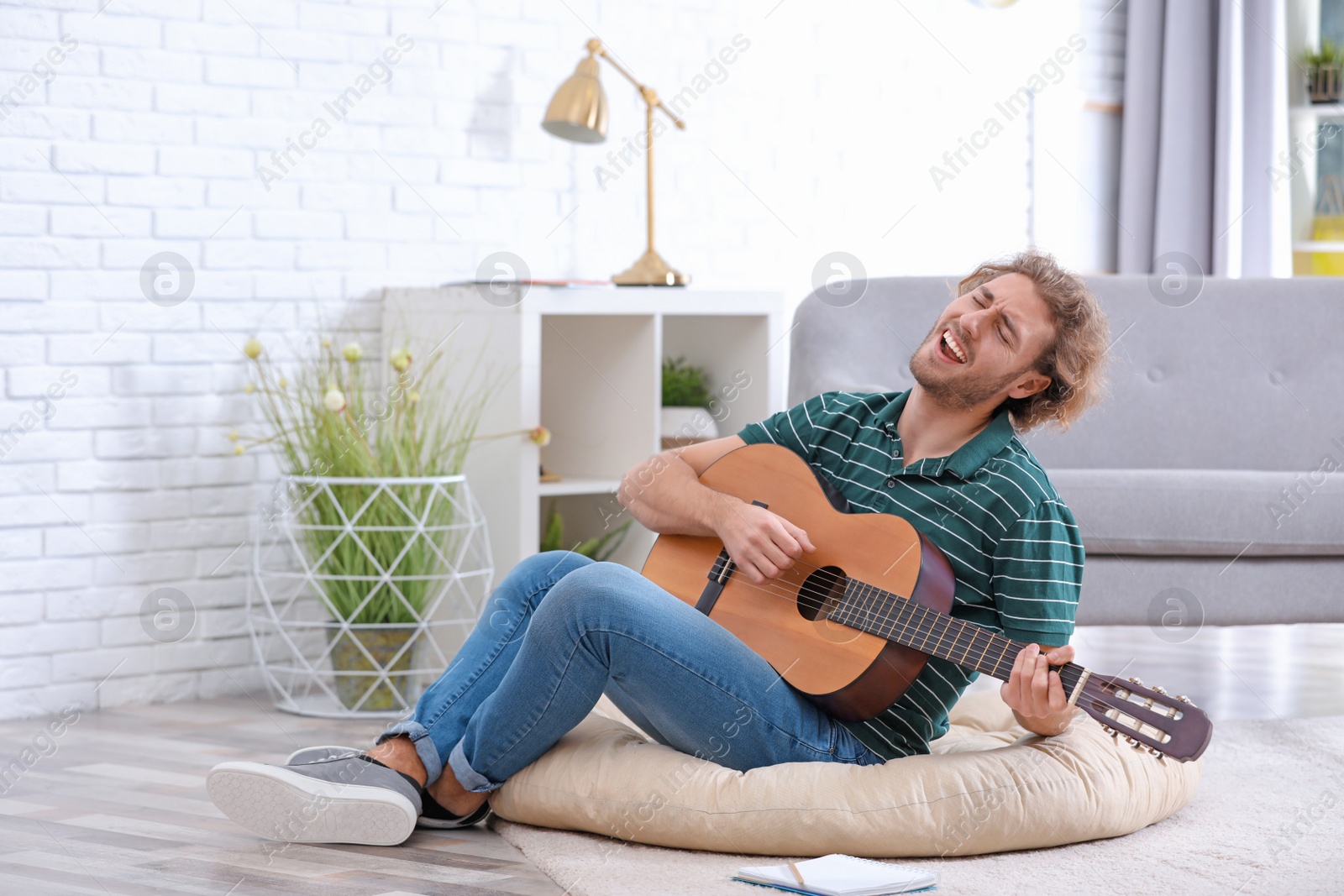 Photo of Young man playing acoustic guitar in living room