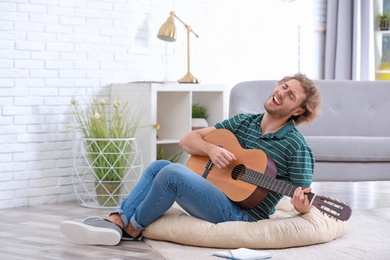 Young man playing acoustic guitar in living room