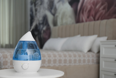 Photo of Modern air humidifier on table indoors. Space for text