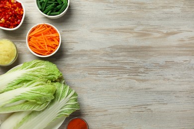 Photo of Fresh Chinese cabbages and other kimchi ingredients on wooden table, flat lay. Space for text