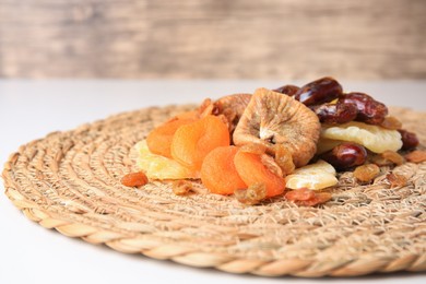 Photo of Pile of different tasty dried fruits on wicker mat, closeup. Space for text