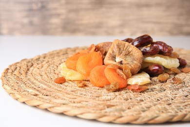 Pile of different tasty dried fruits on wicker mat, closeup. Space for text