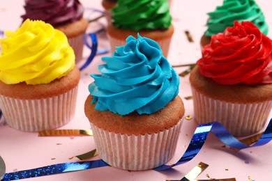 Many delicious colorful cupcakes and confetti on pink table, closeup