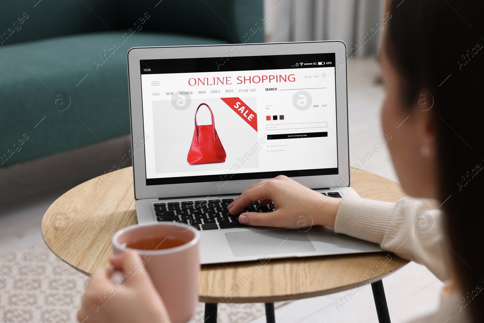 Photo of Woman with cup of tea shopping online during sale on laptop at home, closeup