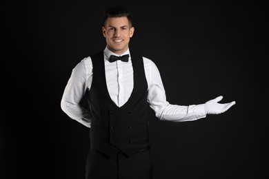 Handsome butler in elegant uniform on black background