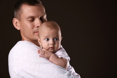 Photo of Happy father with his little baby on dark background. Space for text