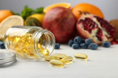 Photo of Vitamin pills, bottle and fresh fruits on white wooden table. Space for text