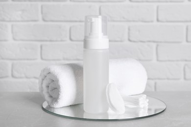 Photo of Bottle of face cleansing product, towel, cotton pads and buds on grey table. Space for text