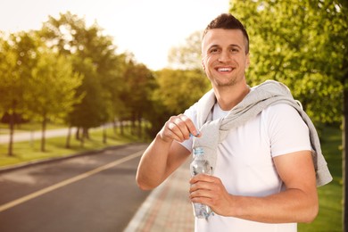 Young man with bottle of water outdoors. Morning fitness