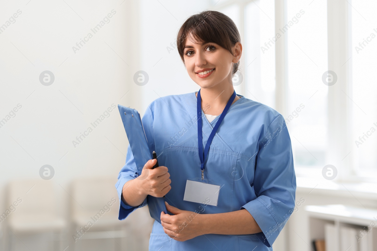 Photo of Portrait of smiling medical assistant with clipboard and pen in hospital