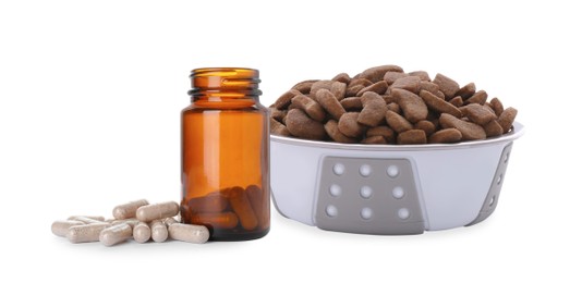 Image of Dry pet food in feeding bowl and bottle with vitamin pills on white background