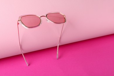 Stylish sunglasses on pink background. Space for text