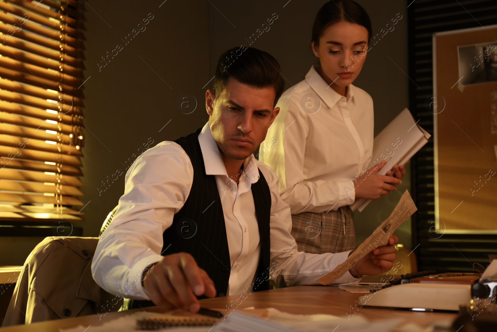 Photo of Old fashioned detective and his colleague working in office