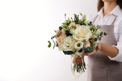 Photo of Florist holding beautiful wedding bouquet on white background, closeup