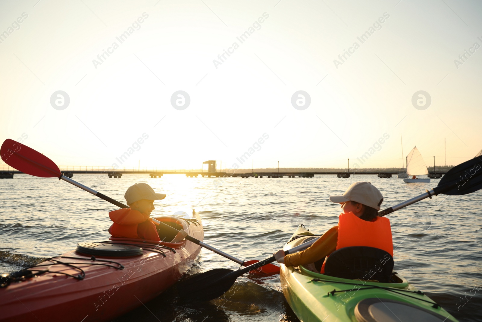 Photo of Little children kayaking on river, back view. Summer camp activity