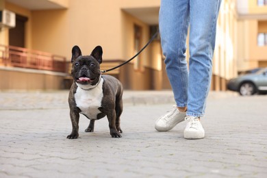 Woman walking with cute French Bulldog outdoors, closeup