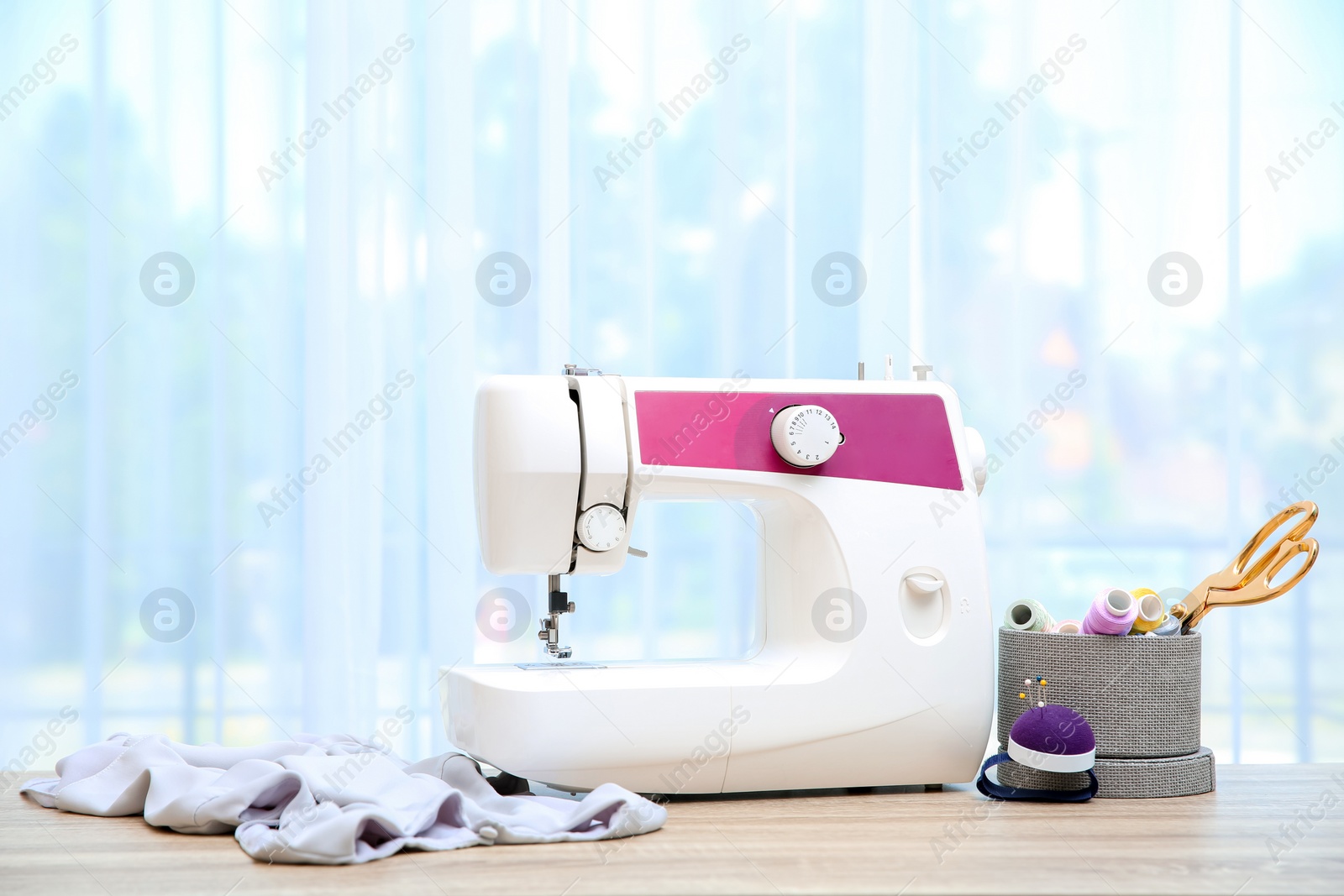 Photo of Sewing machine on table near window indoors