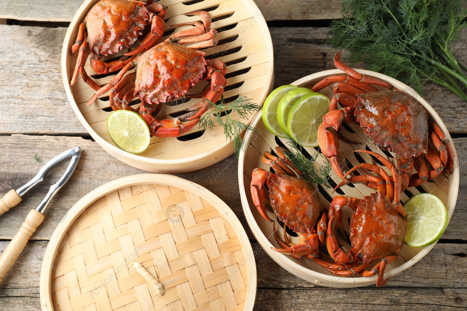 Photo of Delicious boiled crabs with lime on wooden table, flat lay