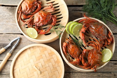 Photo of Delicious boiled crabs with lime on wooden table, flat lay